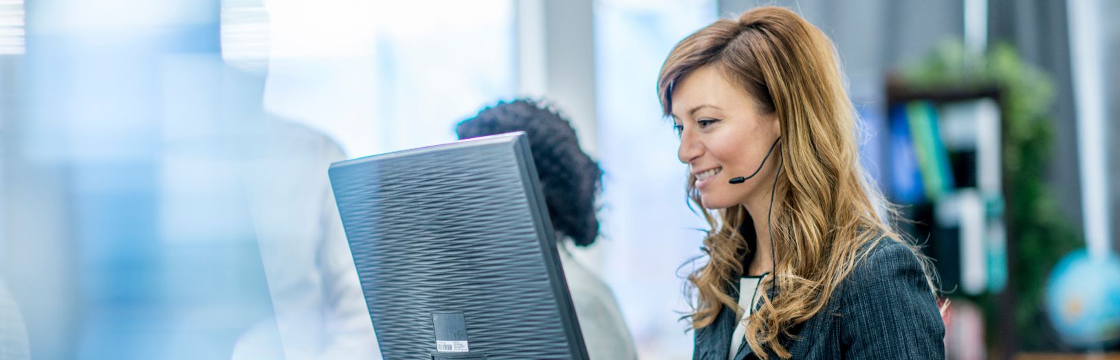 smilende receptionist ved computer