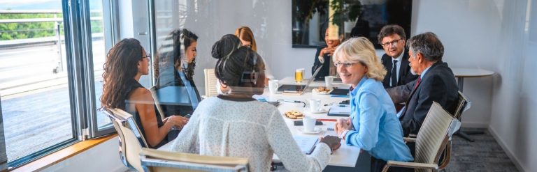 Mennesker i mødelokale med forplejning
