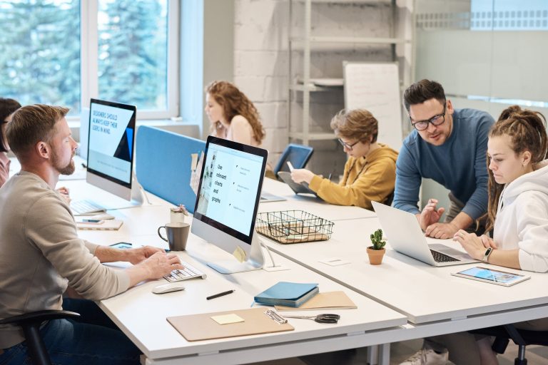 Team in office by their desks with their desktops